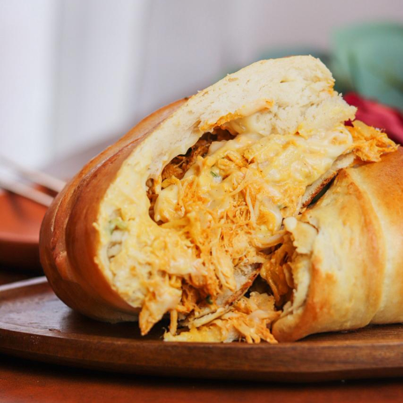 Pão artesanal, recheado com frango desfiado e cream cheese, finalizado com gergelim preto.