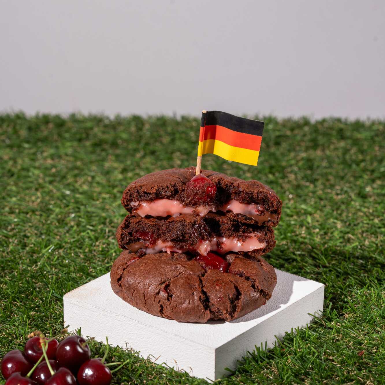 Cookie de cacau intenso com chocolate meio amargo, recheado com brigadeiro de chocolate branco com cerejas silvestres, finalizado com cereja.
Uma releitura de um dos doces mais famosos da Alemanha, símbolo de tradição e sofisticação.