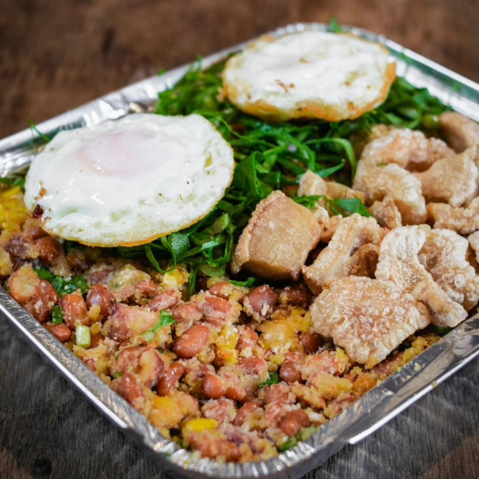 Feijão Tropeiro Família (1kg) – Feijão de primeira com pernil picado, joelho de porco, calabresa, ovos, flocão de milho, farinha de mandioca, torresmos e couve refogada, finalizado com dois ovos fritos por cima. Serve de 3 a 4 pessoas.