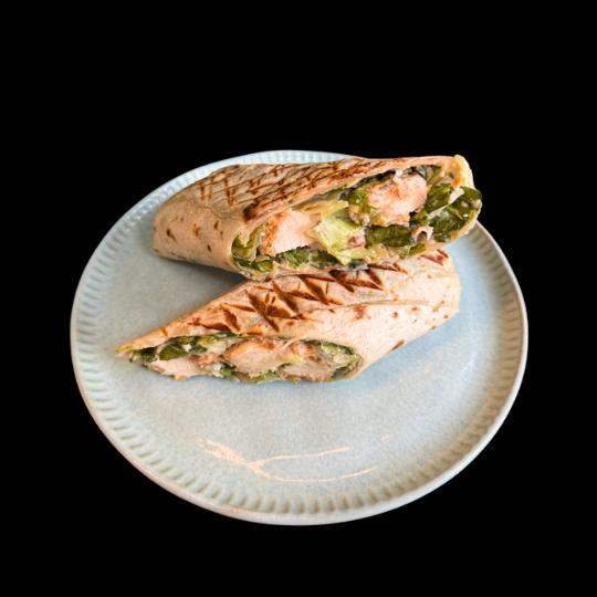 Tortilla recheada de frango grelhado, creme de avocado ao toque de limão, molho pesto, cenoura e mix de folhas. Finalizado na prensa quente.