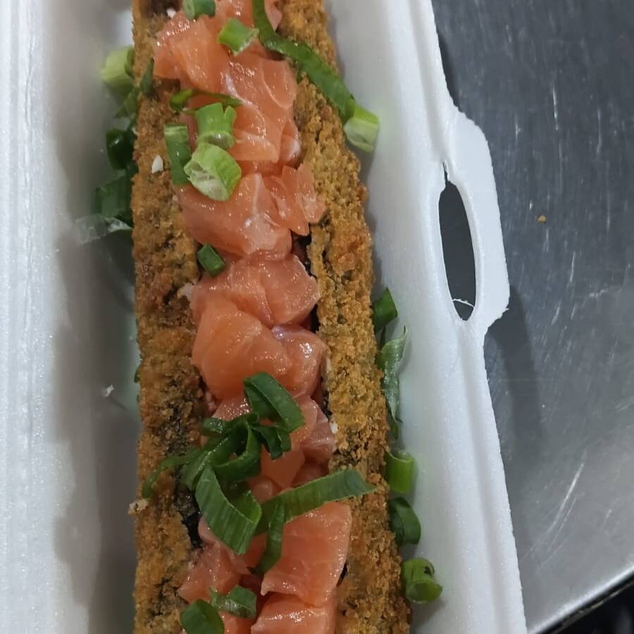 Hot filadélfia cortado ao meio com recheio de cream cheese, salmão por cima e cebolinha.