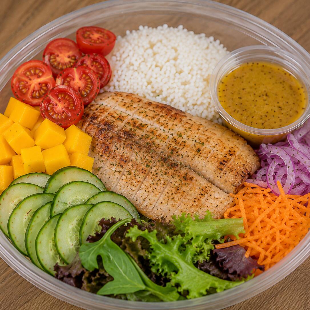 Arroz, tilapia grelhada, manga em cubos, pepino japones, tomate cereja, cenoura ralada, cebola roxa fatiada, mix de folhas e molho de mostarda e mel (520g com o molho)