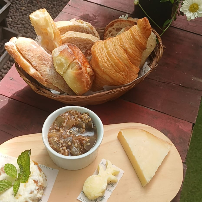 Cesta de pães selecionados, caponata, pastinha de damasco, manteiga de vinho e queijo montanhês