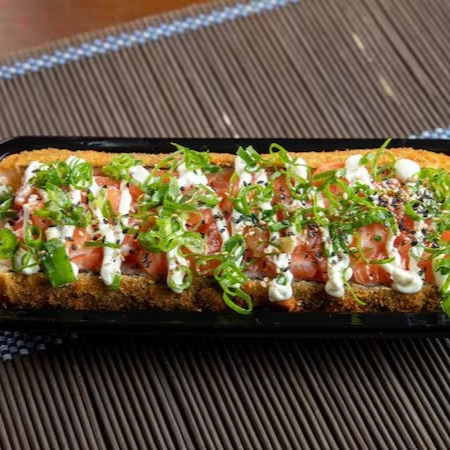 Hot empanado cortado ao meio com recheio de salmão cru em cubos com cream cheese e cebolinha e gergelim