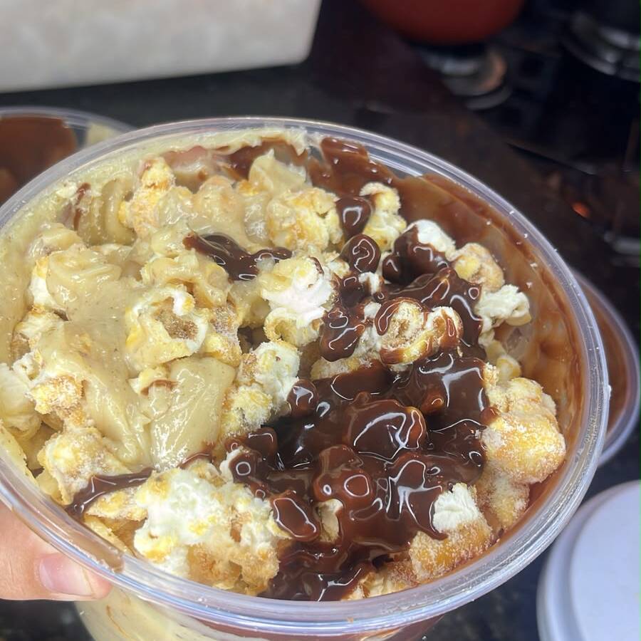 Pipoca caramelizada com leite em pó polvilhado.
Cobertura de creme de avelã, com brigadeiro de leite em pó