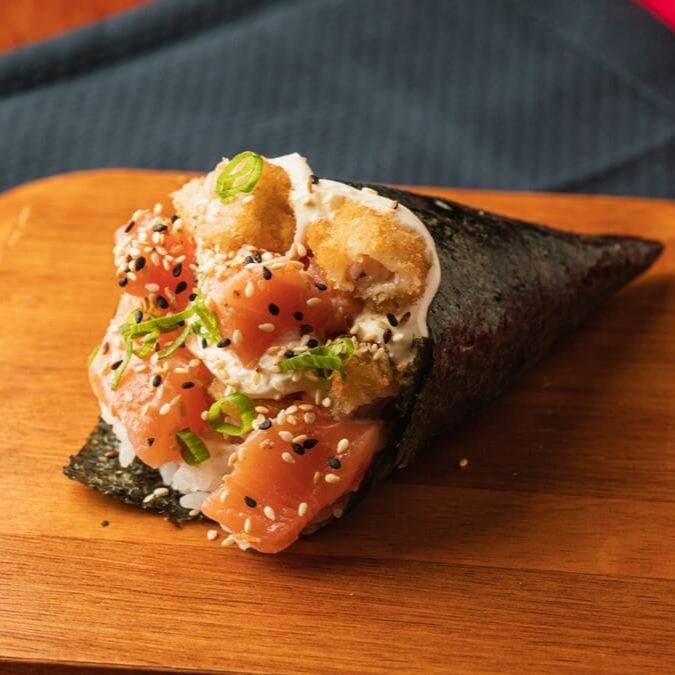 Temaki enrolado na alga com recheio de salmão natural e camarão empanado e cream cheese .