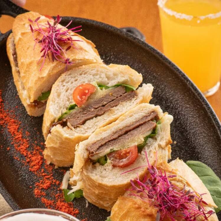 Pão baguete crocante recheado com filé de frango empanado, queijo derretido, rúcula fresca e tomate. Um sanduíche artesanal bem servido, crocante por fora, suculento por dentro e cheio de sabor.