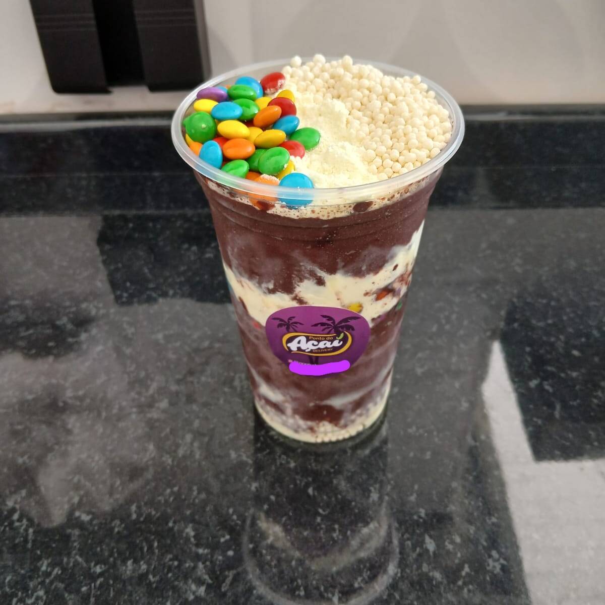 Açaí montado com Confetes de chocolate, Leite em pó ,Granulado, Flocos de Cereais e
Calda de Chocolate: no copo de 500ml.