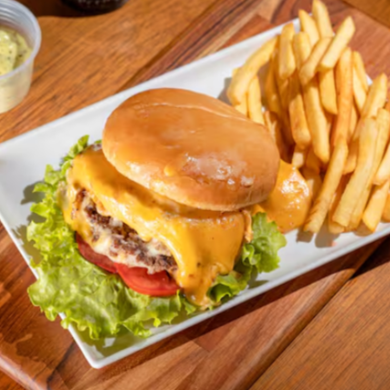 Delicioso hambúrguer bovino de 120g com generosas fatias de queijo, prato, tomate e alface, requeijão e azeitona
