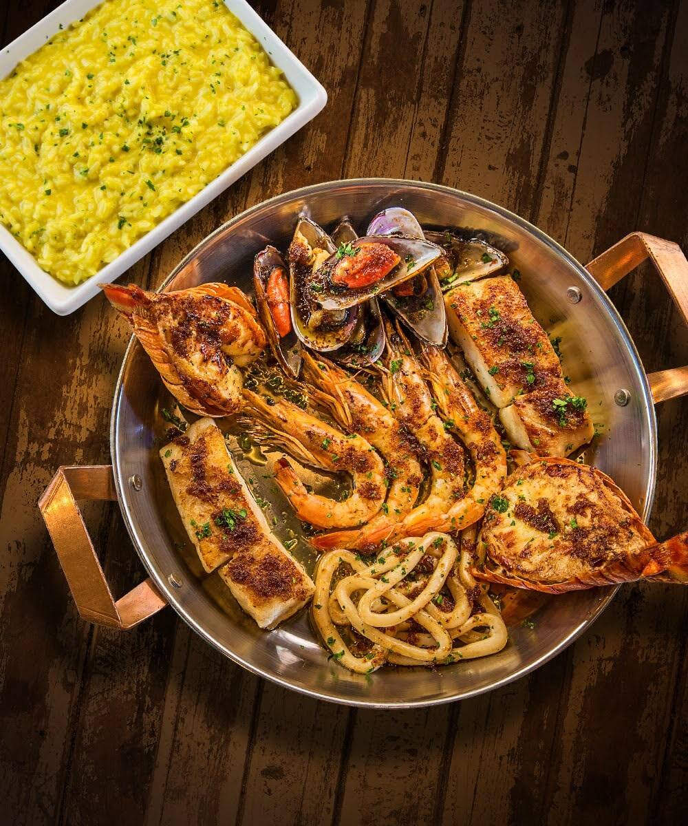 Indescritível prazer do mar nordestino. Lagosta, camarão, mexilhões, peixe e lula grelhados com molho provençal. Acompanha arroz de açafrão.Tamanho do camarão nesse prato: 30g.