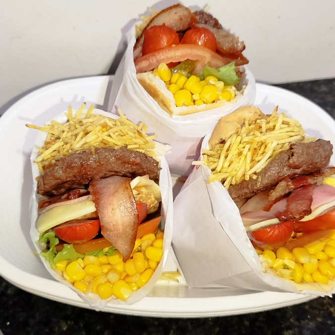 Hambúrguer Bovino acompanhado de Mussarela, Apresuntado, Bacon, Salsicha, Ovo, Tomate, Alface, Milho e Batata Palha.