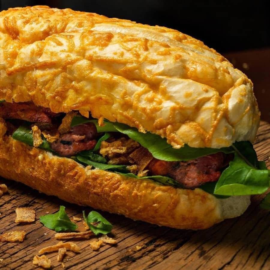 Baguete de parmesão ou gergelim, 200g de linguiça fresca temperada, bacon, alface, maionese e exclusivo molho (chimichurri) tradicionalmente argentino.