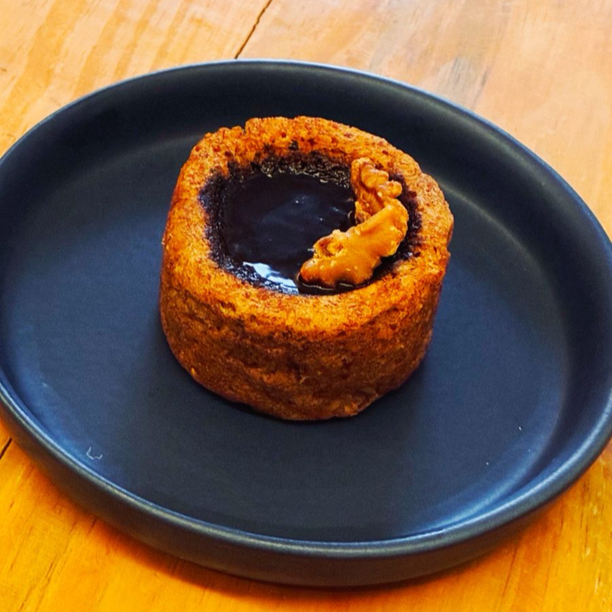 Bolo de banana com pasta de amendoim, servido quentinho com cobertura de ganache de chocolate meio amargo com leite de aveia. Contém glúten.