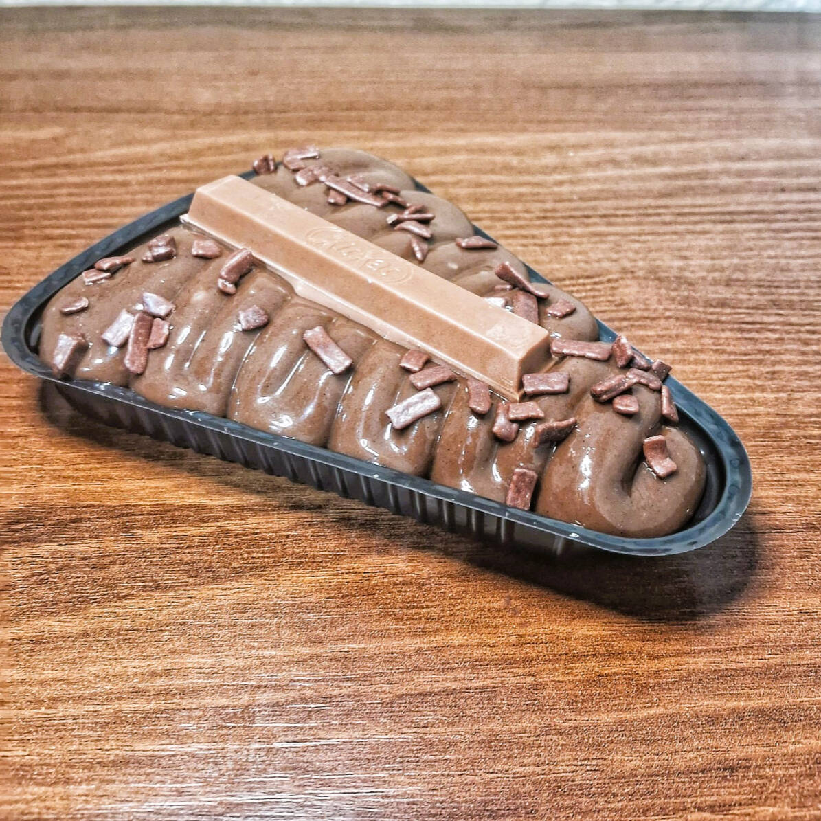 Brownie de chocolate meio amargo com cobertura de brigadeiro cremoso, decorado com granulado e com um pedaço de KitKat. Uma fatia mais crocante e chocolatuda, com contraste entre o macio do brigadeiro e o crocante do KitKat.