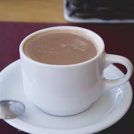 Bebida aconchegante, feita com chocolate e leite quente, resultando em um sabor intenso e textura aveludada.