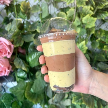 Copo composto por: Pedaços de chocolate Mousse de chocolate Mousse de maracujá