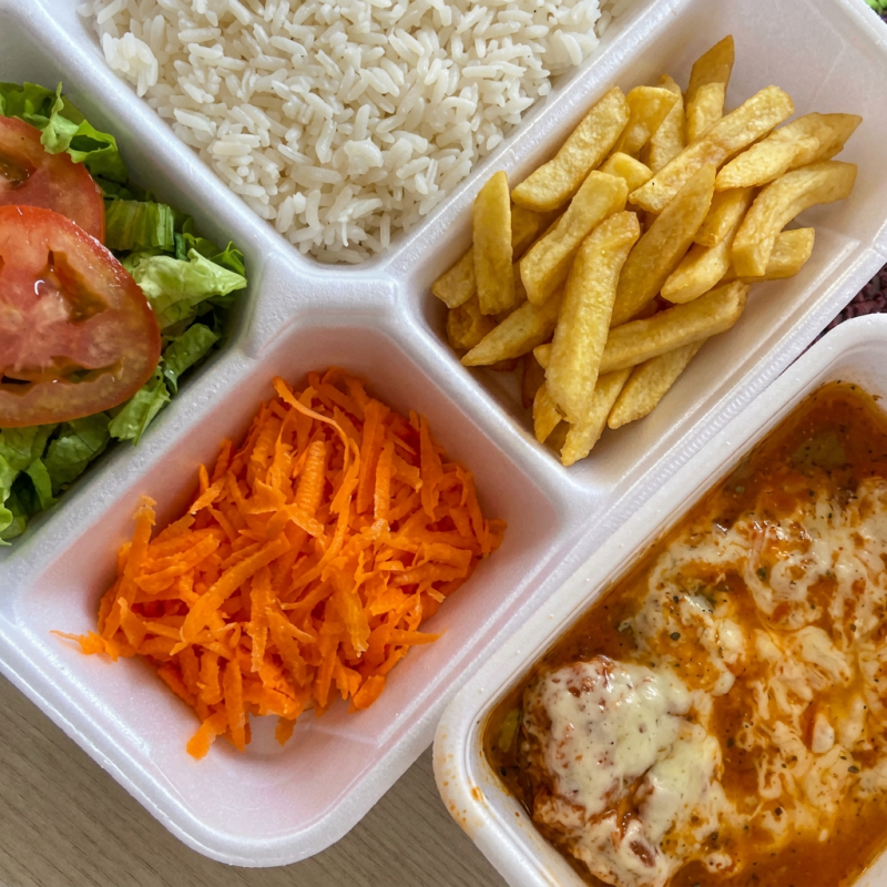 Filé de frango empanado, dourado e crocante, coberto com molho de tomate caseiro e uma generosa camada de queijo derretido e gratinado. Servido de forma organizada em divisória: arroz soltinho, batata frita crocante e a parmegiana separada, garantindo sabor e apresentação impecável em cada garfada.