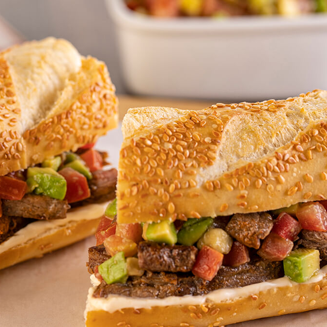 Saboroso sanduba de contra filé acebolado com vinagrete fresco e queijo derretido.
