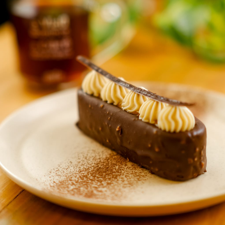 Sobremesa gelada de textura cremosa à base de chocolate intenso. Com camada crocante delicada envolvida por cobertura de chocolate com avelãs. Recebe o contraste elegante de uma camada aveludada de caramelo e de mousse de avelã. Coroado por arabesco de chocolate amargo.