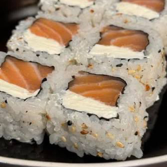 Rolo de sushi invertido com salmão e cream cheese, cobertos com gergelim.