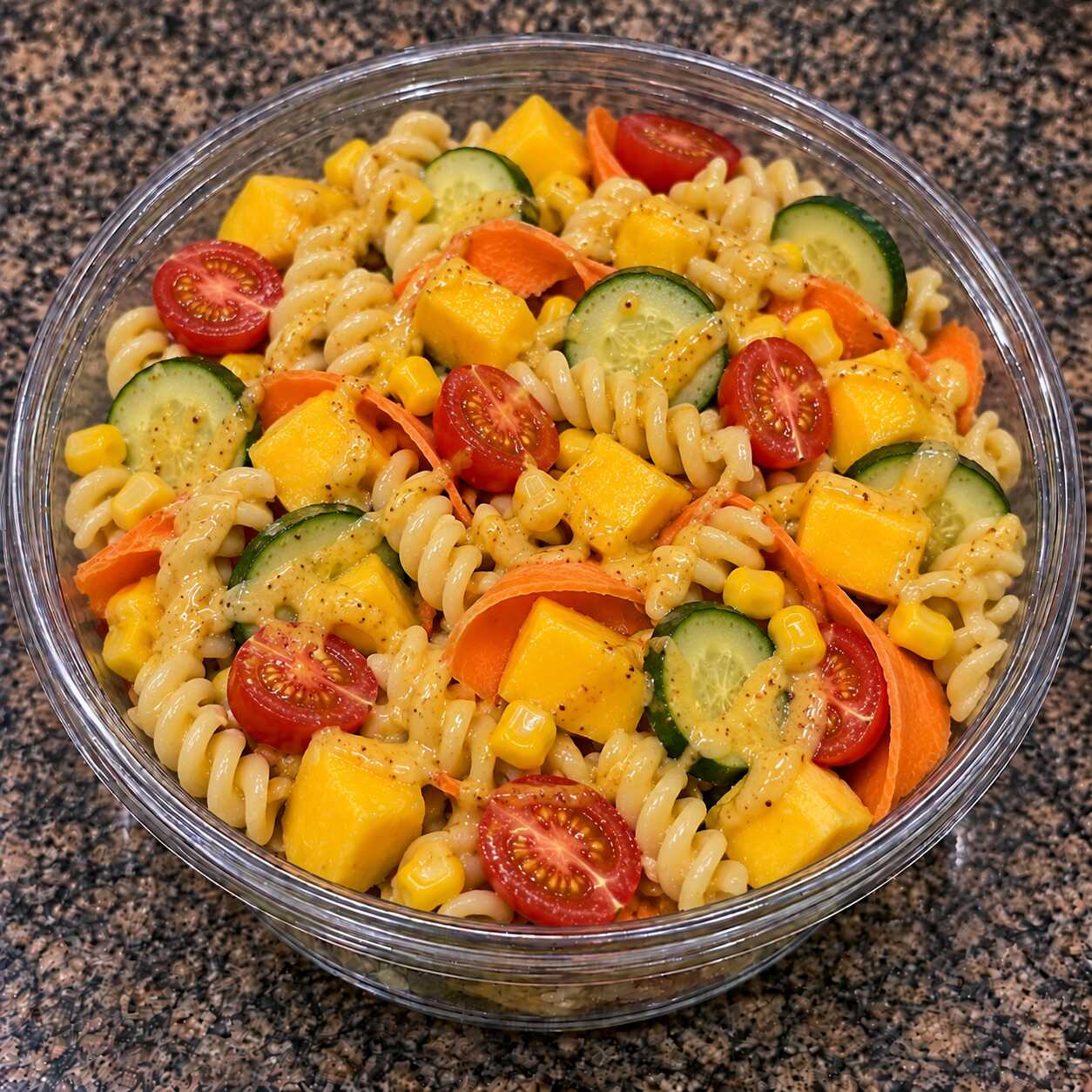 Leve, agridoce e refrescante: macarrão com manga, tomate-cereja, milho, cenoura, pepino e molho de mostarda e mel.