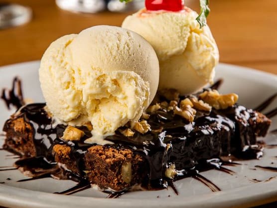 Bolo de chocolate americano com nozes. Coberto com calda de chocolate quente e sorvete de creme.