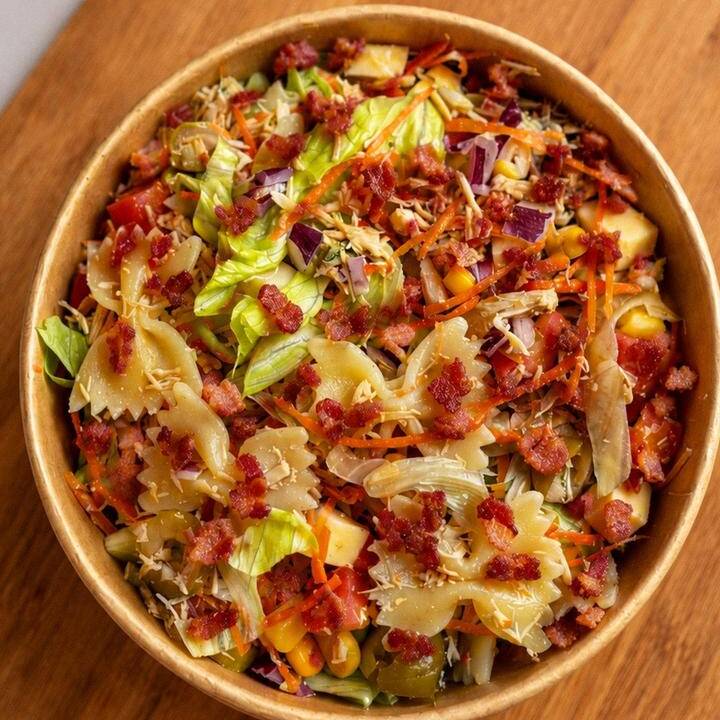 Uma combinação completa e bem servida com frango desfiado, macarrão gravata, mix de alfaces frescas (crespa e mimosa), milho, azeitonas, tomate, cenoura ralada, cebola roxa, cubos de muçarela, bacon crocante e croutons crocantes. Acompanha molho especial da casa, enviado à parte para você finalizar do seu jeito.
Refeição de verdade, com um toque extra de sabor e crocância.