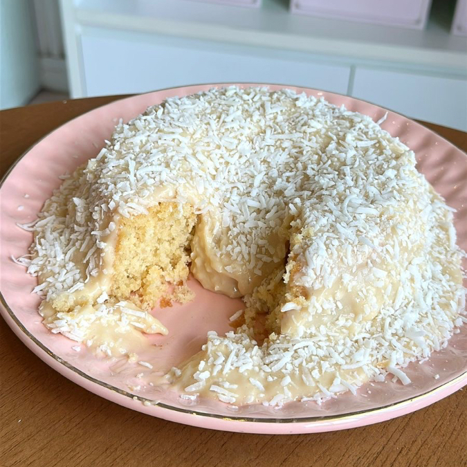 Massa fofinha de bolo de baunilha com calda de brigadeiro de coco e pedaços de coco ralado.