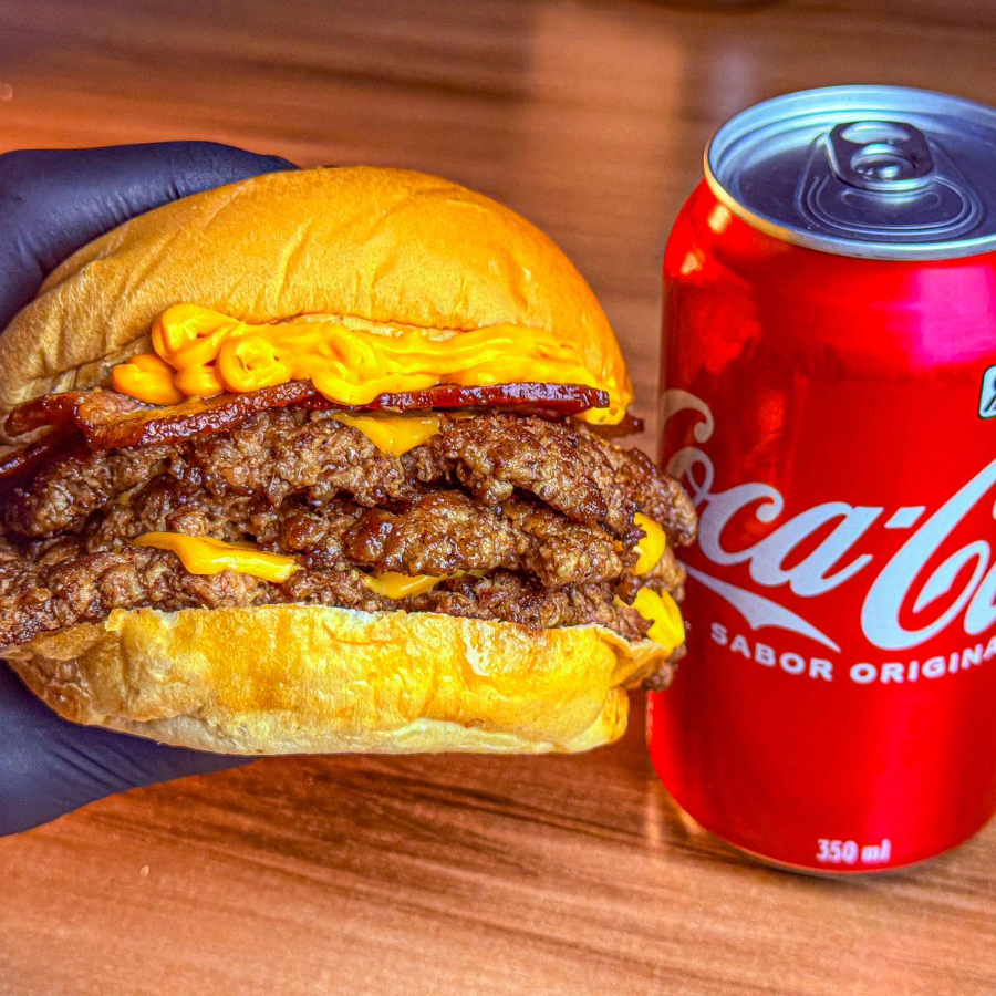 Pão brioche, 3 hambúrgueres smash de 70g, bacon, cheddar e maionese bodega. Acompanha coca cola lata caso queira trocar por coca cola zero favor colocar nas obs