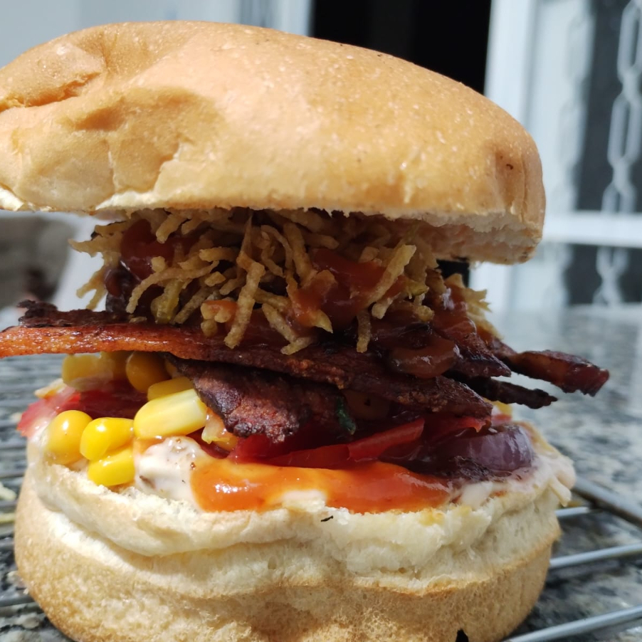 Uma explosão de sabores e texturas! O Crocante Supremo combina camadas generosas de bacon crocante, milho doce, tomate fresco e cebola roxa, finalizados com muita batata palha douradinha. Tudo isso regado com ketchup e maionese cremosa no pão tradicional macio. Um lanche irresistível, feito pra quem ama crocância em cada mordida!