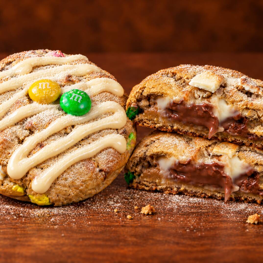 Massa tradicional. Gotas de chocolate branco nobre e m&ms. Recheio de ninho e nutella. Finalizado com brigadeiro de ninho e uma camada de leite ninho por cima.(aprox.70g)