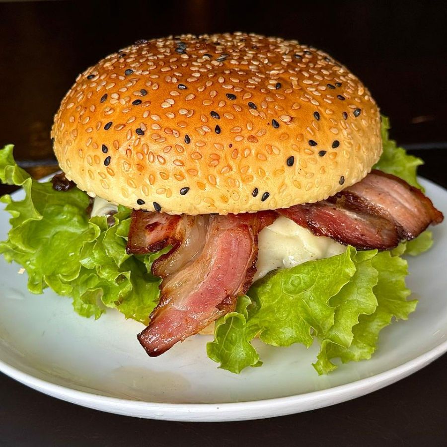 O nosso X-Burguer Bacon é uma verdadeira obra-prima da culinária gourmet. Composto por um irresistível pão gourmet, macio e delicioso, abriga uma generosa camada de carne bovina suculenta e de alta qualidade. A mussarela derretida, com seu sabor suave e textura cremosa, complementa perfeitamente o sabor marcante do bacon crocante. O molho barbecue, com seu adocicado picante, adiciona um toque especial ao conjunto. A alface fresca e o tomate maduro, por fim, acrescentam a refrescância necessária para equilibrar todos esses sabores. É uma experiência gastronômica incrível que você não pode deixar de provar!
