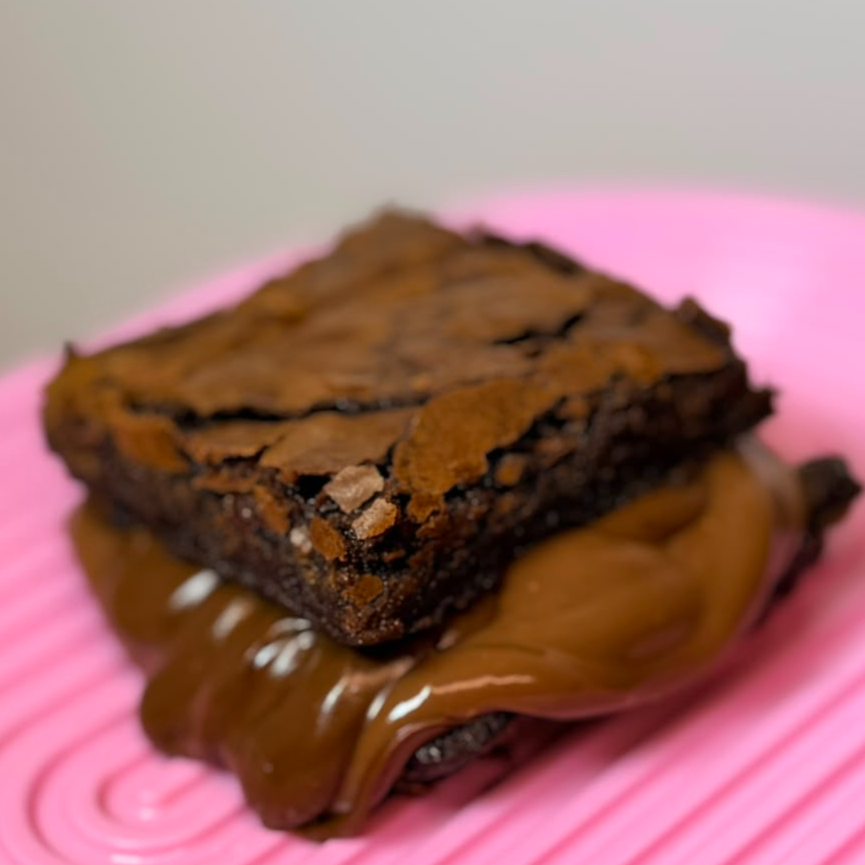 Prepare-se para uma experiência única com o nosso Sandobrownie! Feito com um brownie rico e irresistivelmente macio, recheado com um creme de brigadeiro super cremoso que vai fazer você se sentir nas nuvens. Cada pedaço traz a verdadeira essência do brigadeiro, combinando o sabor intenso do chocolate com a suavidade do doce. Uma explosão de sabor que vai deixar você querendo mais!