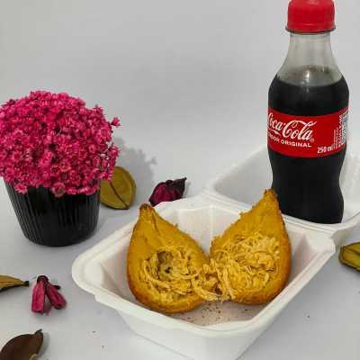 Coxinha recheada com frango desfiado e temperos especiais, envolta em uma massa crocante e uma coca de 250ml.