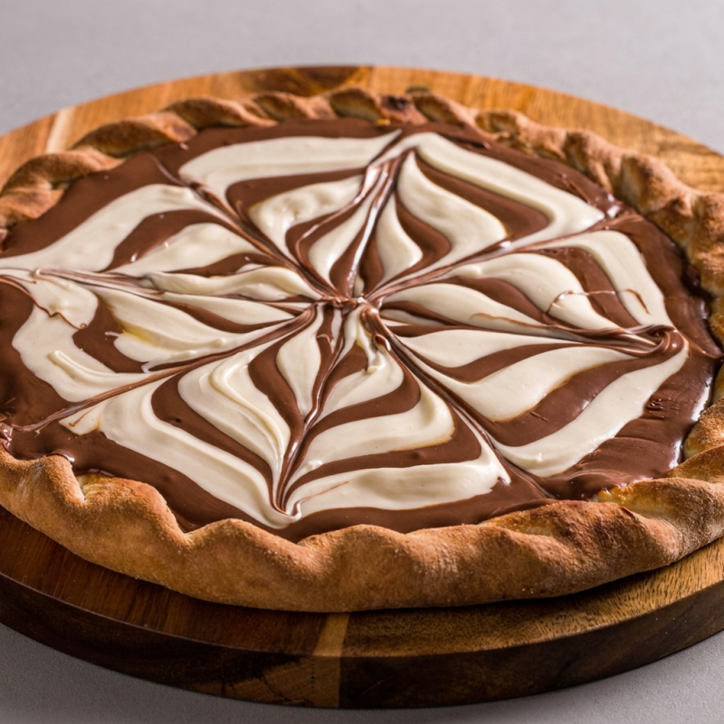 Feita com nossa massa artesanal doce, coberta com uma camada generosa de creme de leite cremoso, chocolate branco e chocolate preto derretido, e finalizada com um toque de leite condensado. (4 fatias)