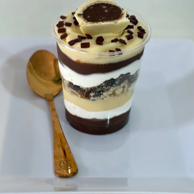 Com brigadeiro de chocolate intercalado com mousse de ninho e brigadeiro de ninho, pedaços de ouro branco no meio e finalizado com ouro branco