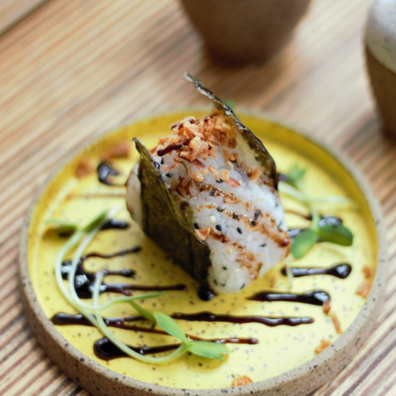 Bolinho de arroz recheado com tartar de shimeji e creme de castanha de caju finalizado com cebola crispy e tarê.