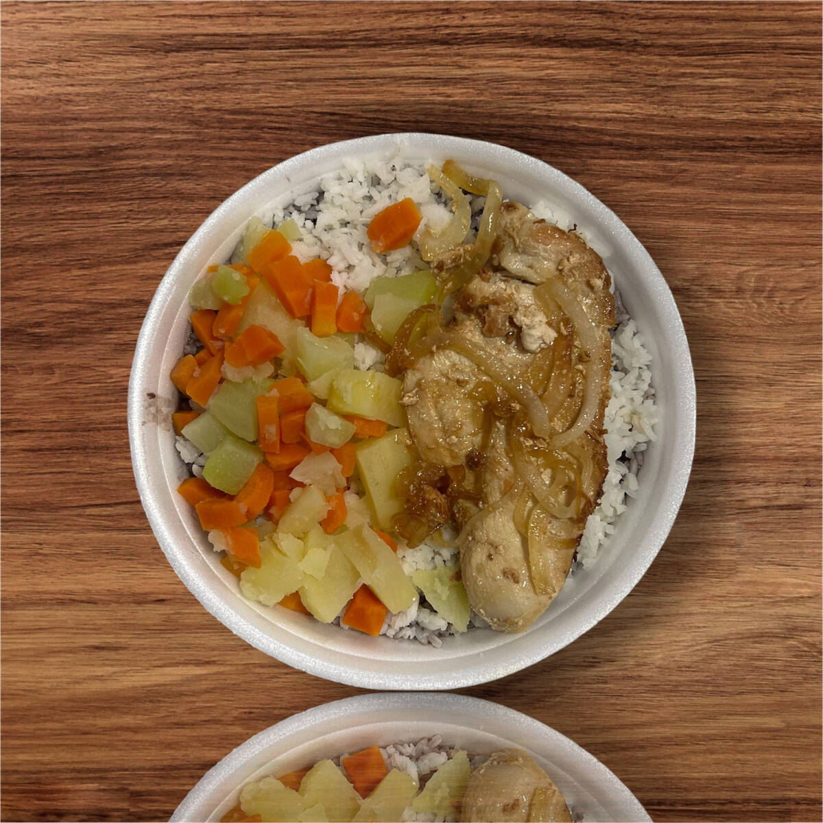 Marmita acompanha arroz branco, feijão preto, farofa e legumes cozidos.