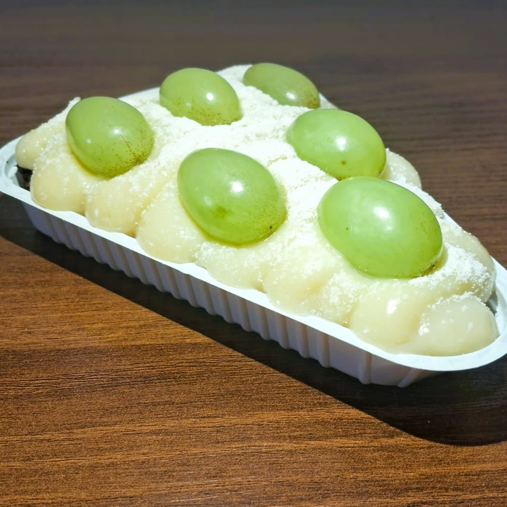 Fatia de brownie de chocolate meio amargo, cremoso e molhadinho, coberto com leite Ninho e decorado com uvas verdes sem semente. Uma combinação equilibrada entre o chocolate mais intenso, o sabor suave do Ninho e o frescor da uva.