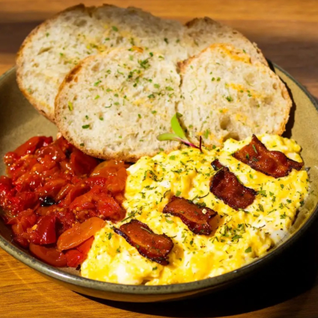2 ovos mexidos cremosos preparados com manteiga e creme de leite. Acompanham tomatinhos confitados, bacon e fatias de pão italiano de fermentação natural.