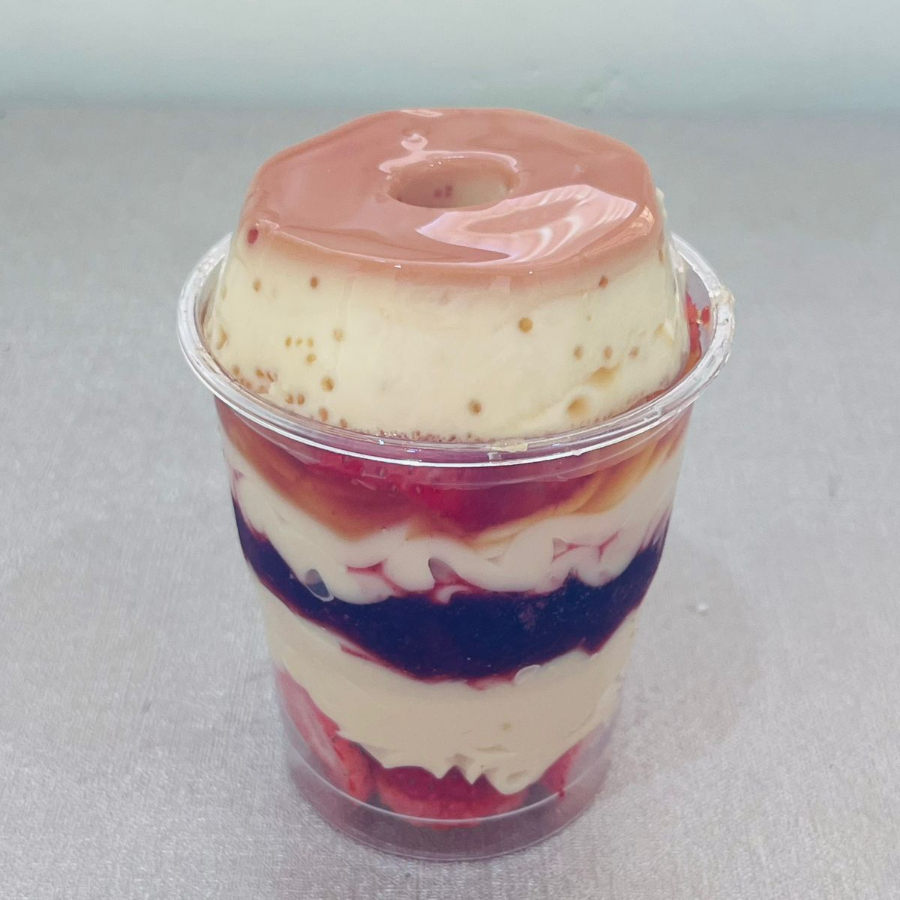 Copo com creme de chocolate branco, geleia artesanal de morango, camada de morangos frescos e finalizado com pudim.