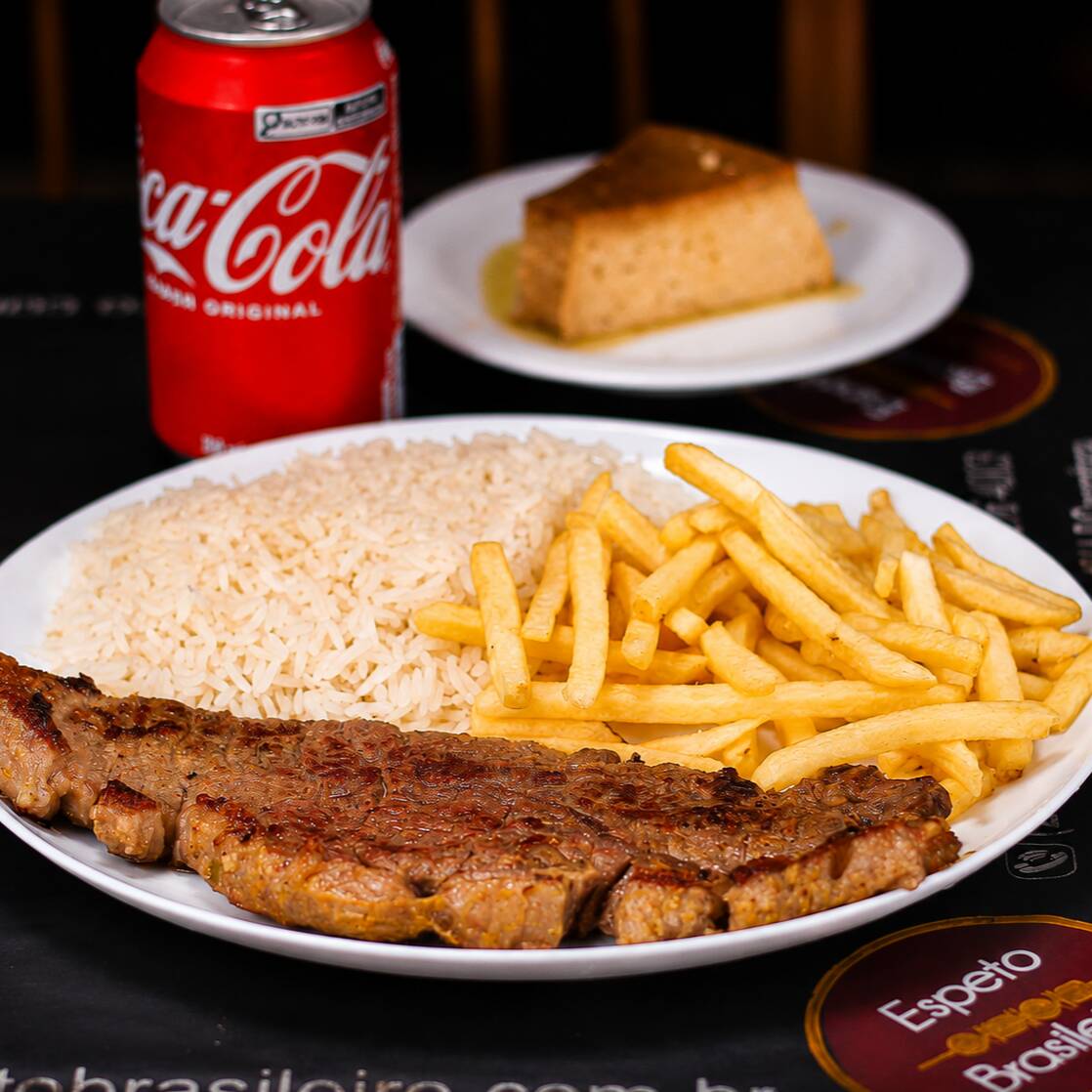 Contra filé grelhado com cebola douradinha, bem suculento. Acompanha pudim de leite condensado feito na casa, com calda de caramelo e uma Coca-Cola lata bem gelada. Combo completo pra você aproveitar!