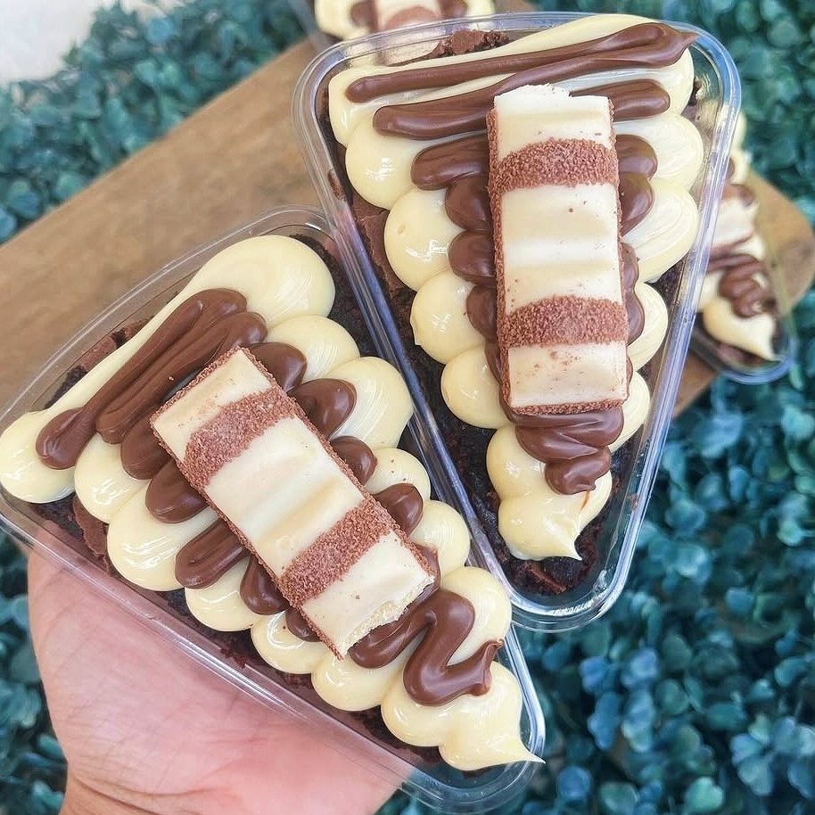 Fatia de brownie bem molhadinho com casquinha crocante, coberto com brigadeiro de ninho, nitella e kinder bueno, finalizado com granulado de chocolate