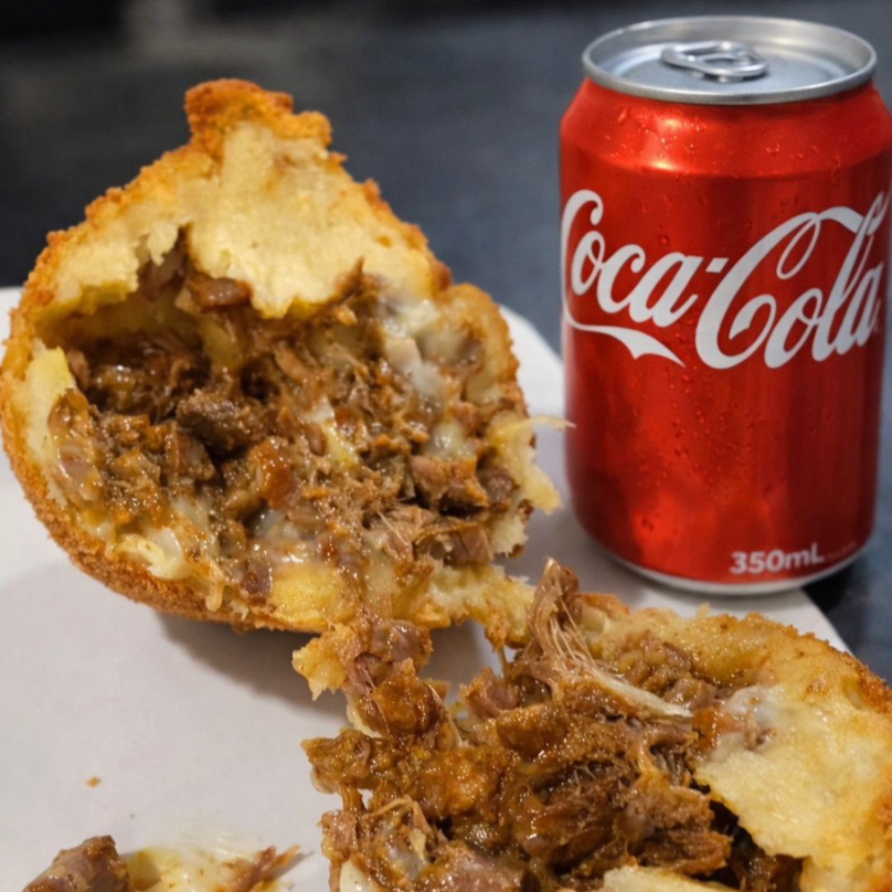 Crocante por fora, suculenta por dentro 😍 Coxinha recheada com carne desfiada e requeijão, acompanhada de refrigerante lata 350ml. O combo perfeito pra matar a fome!