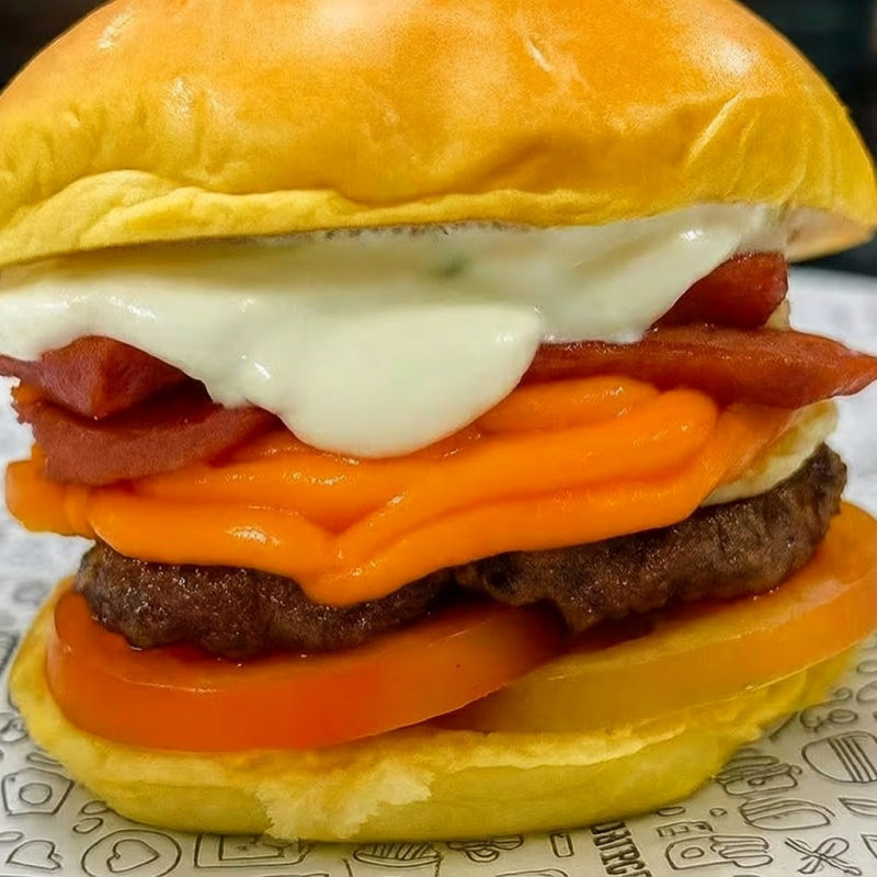 Pão de brioche,carne,ovo,queijo cheddar,calabresa,tomate e molho da casa.