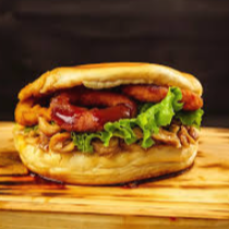 Pão de brioche selado na maionese artesanal, Hambúrguer artesanal, cheddar cremoso, cebola caramelizada no barbecue, mussarela gratinada e bacon fatiado.