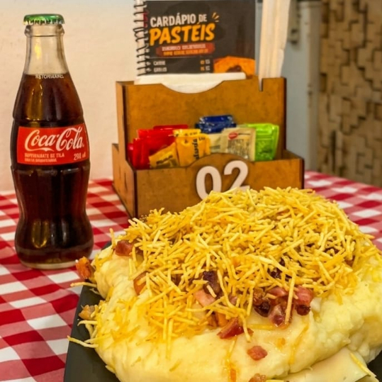 Salsicha, milho, purê de batata, maionese, ketchup, cheddar e batata palha.