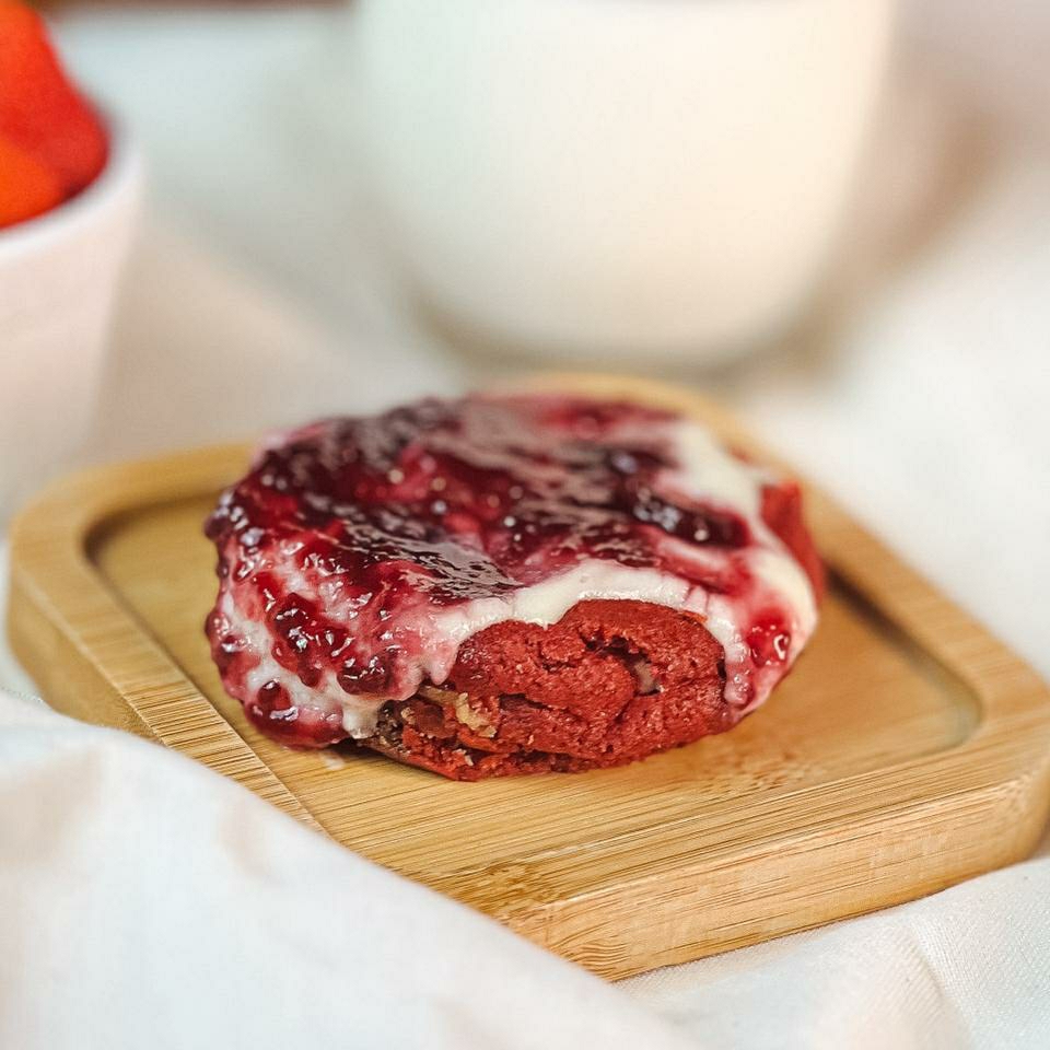 Massa Red Velvet com gotas de chocolate branco, com cobertura secreta a base de cream cheese e geleia de morango.