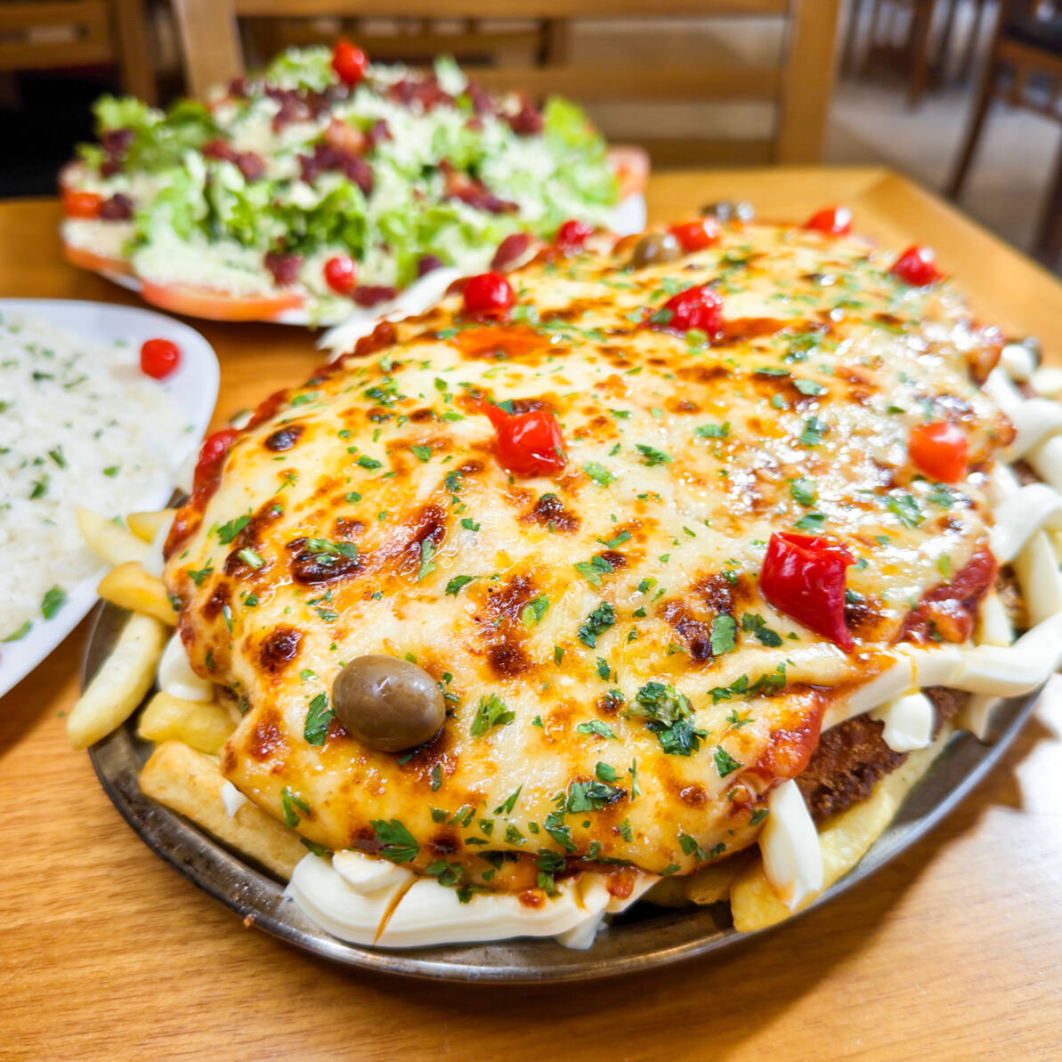 Frango com Carupiry servido ao Molho Vermelho Artesanal e mussarela e gratinado com parmesão. Servido com arroz branco, batatas fritas e salada do Cheff. Serve 3 pessoas
