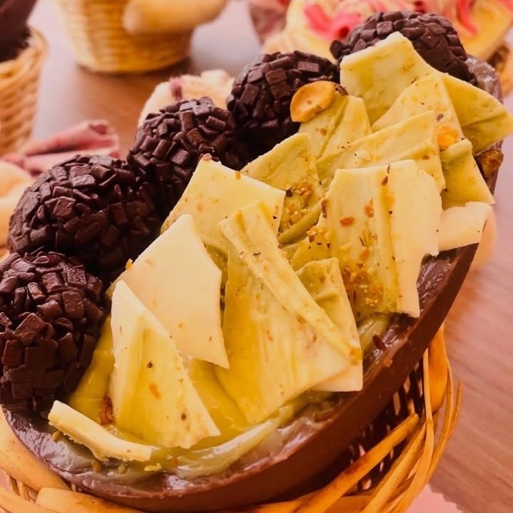 Com uma casca de chocolate rica e crocante, o Ovo Brigatache apresenta um recheio de creme de pistache e brigadeiro cremoso. Decorado com lascas de chocolate branco e pistache, além de brigadeiros boleados, é uma combinação irresistível de sabores e texturas. Ideal para quem aprecia um doce sofisticado e bem equilibrado, proporciona uma experiência única a cada mordida. Pesa em torno 500gr
